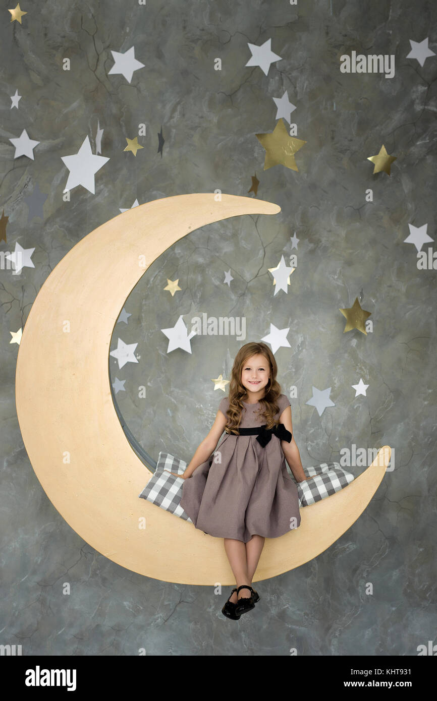 Petite fille dans assis sur grande lune. Petite fille à rêver Banque D'Images