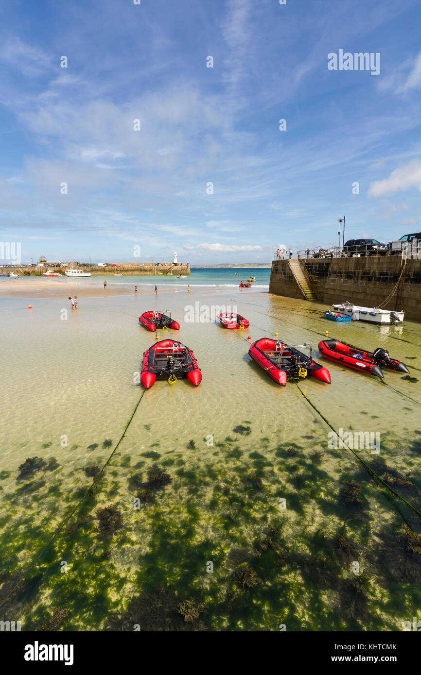 Vue sur la baie de St Ives à marée basse avec bateaux mis à la terre et les gens de la pagaie dans l'eau claire. Banque D'Images