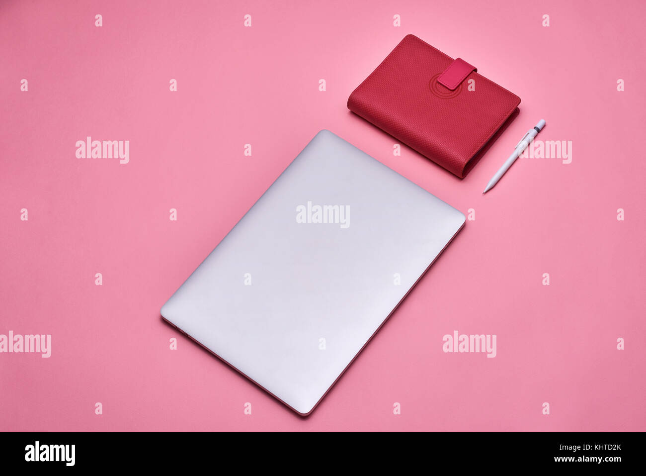 Ordinateur portable avec livre et stylo sur fond rose. Banque D'Images
