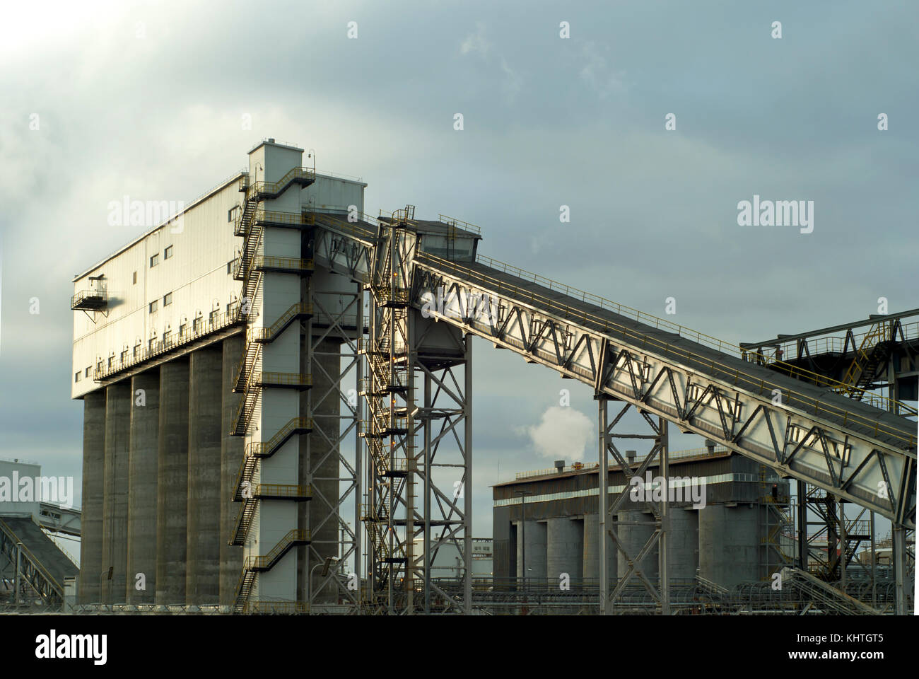 Fragment d'une entreprise industrielle moderne avec des silos pour le stockage de matériaux en vrac et d'un convoyeur à bande incliné couvert Banque D'Images