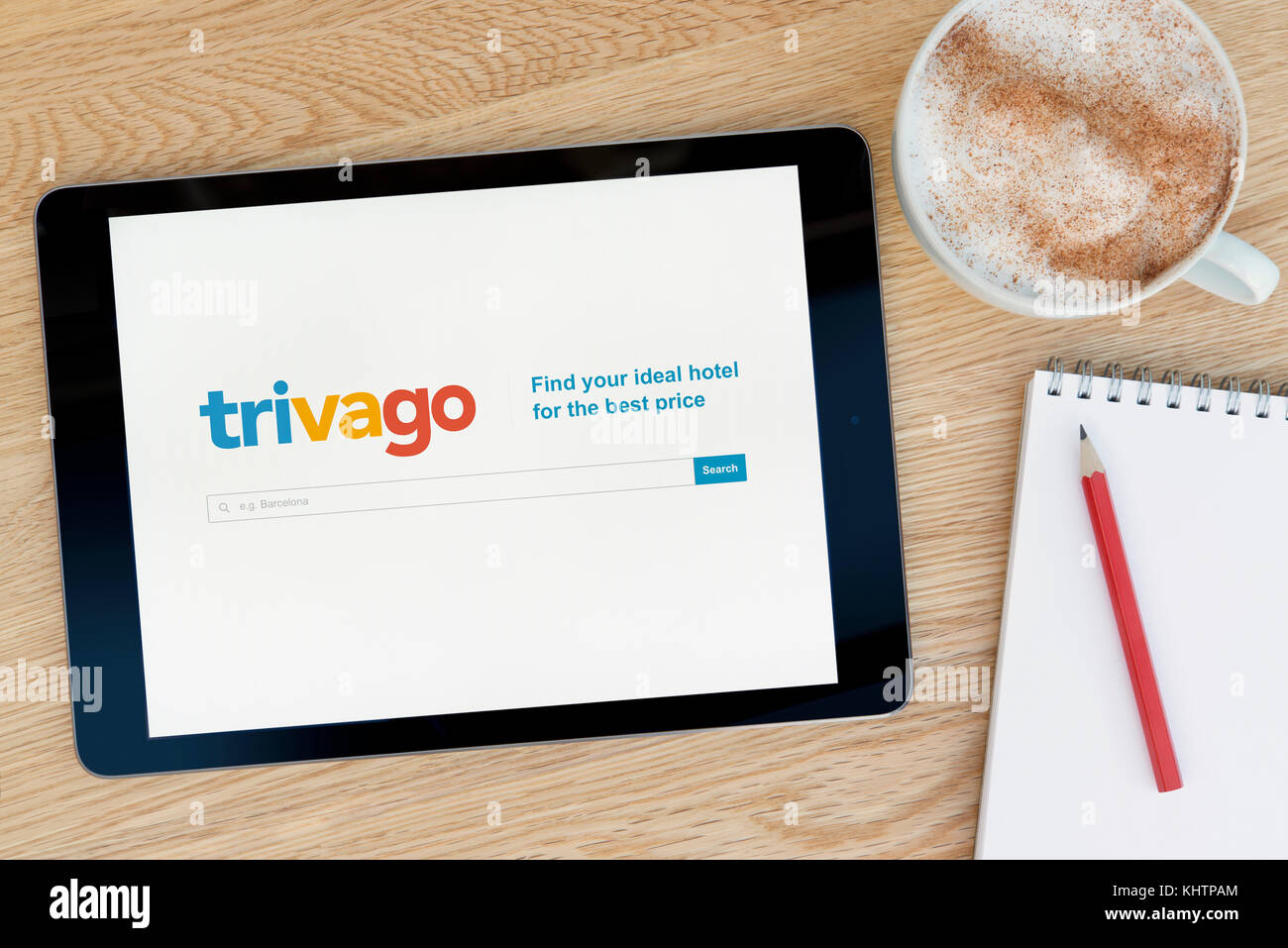 Le site web dispose d'un sur trivago iPad tablet device qui repose sur une table en bois à côté d'un bloc-notes et un crayon et une tasse de café (rédaction uniquement) Banque D'Images