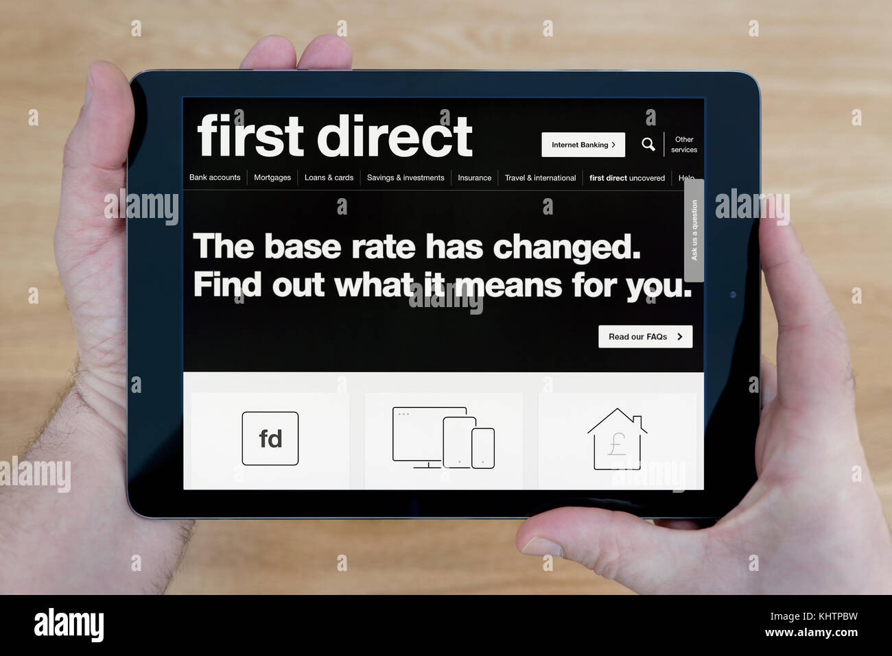 Un homme regarde le premier site web direct sur son iPad tablet device, tourné contre une table en bois page contexte (usage éditorial uniquement) Banque D'Images