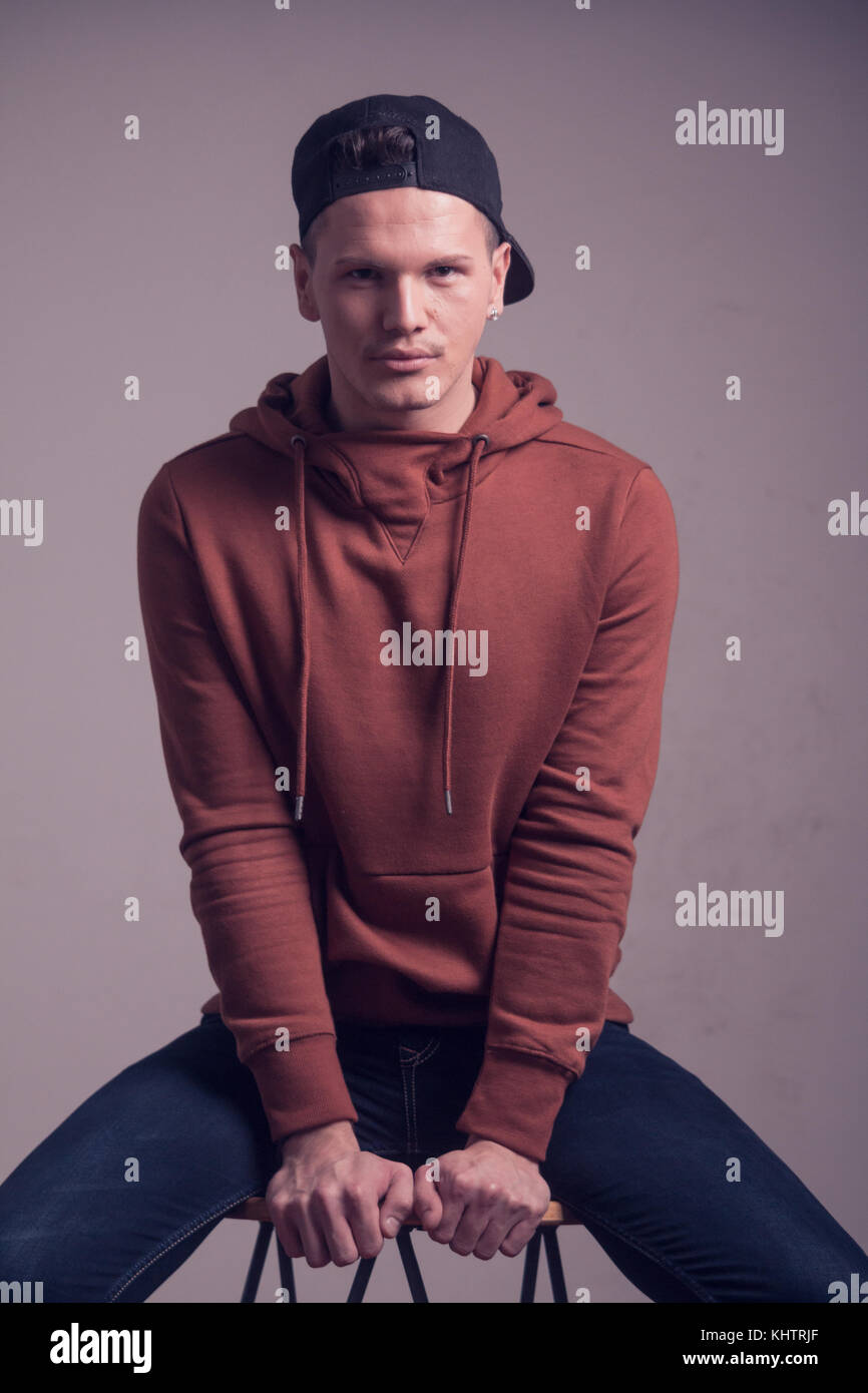Un jeune homme, 20 ans, a l'air de gamin, posant en studio, les tenues, les sweatshirt, haut du corps portrait shot Banque D'Images
