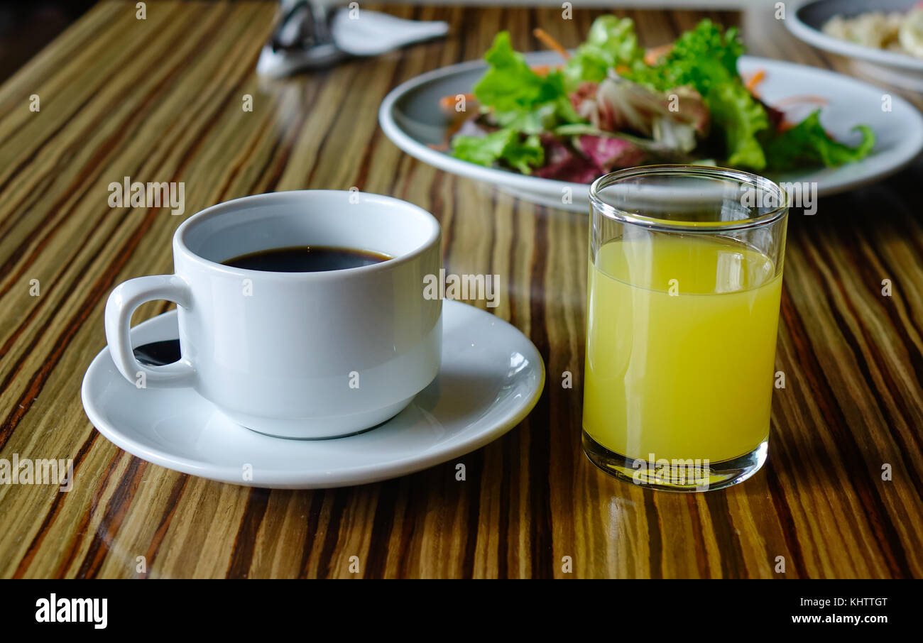 Tasse de café avec un verre de jus de fruit sur la table pour le petit déjeuner. Banque D'Images