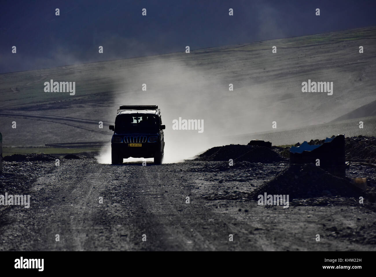 Silhouette de location de jeep sur une route de montagne dans la poussière d'or, l'aube. Banque D'Images