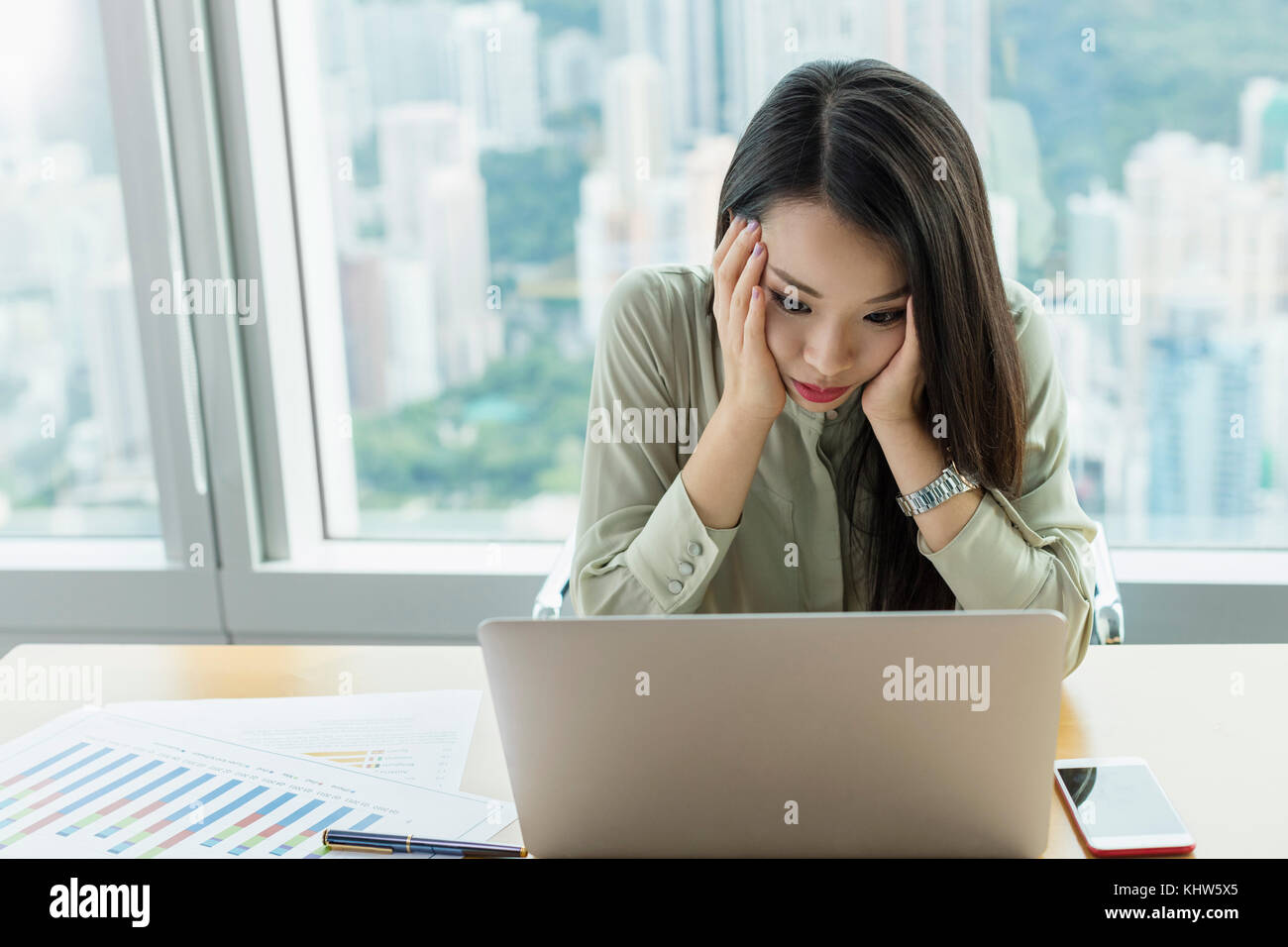 Businesswoman using laptop, la tête dans les mains à la recherche a souligné Banque D'Images