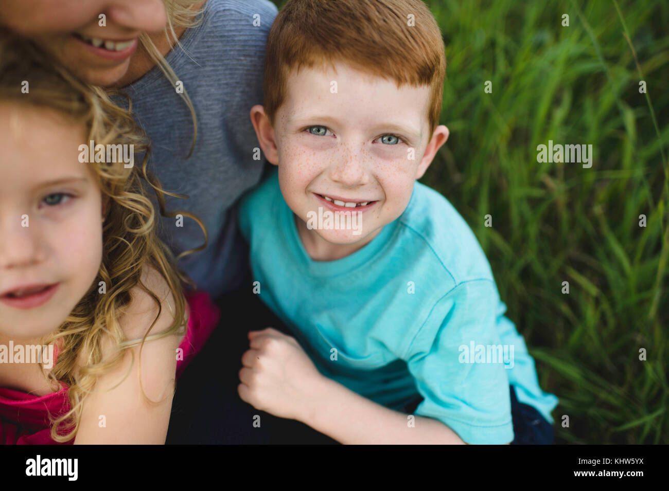Portrait de jeune fille et son frère assis sur les genoux de la mère dans l'herbe Banque D'Images