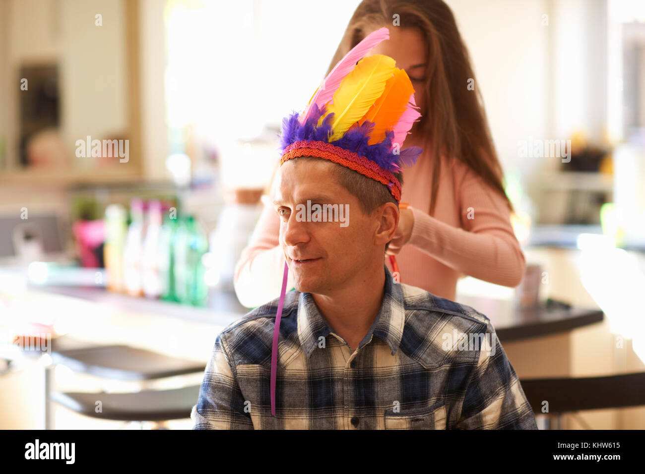 Girl putting coiffure de plumes sur le père Banque D'Images