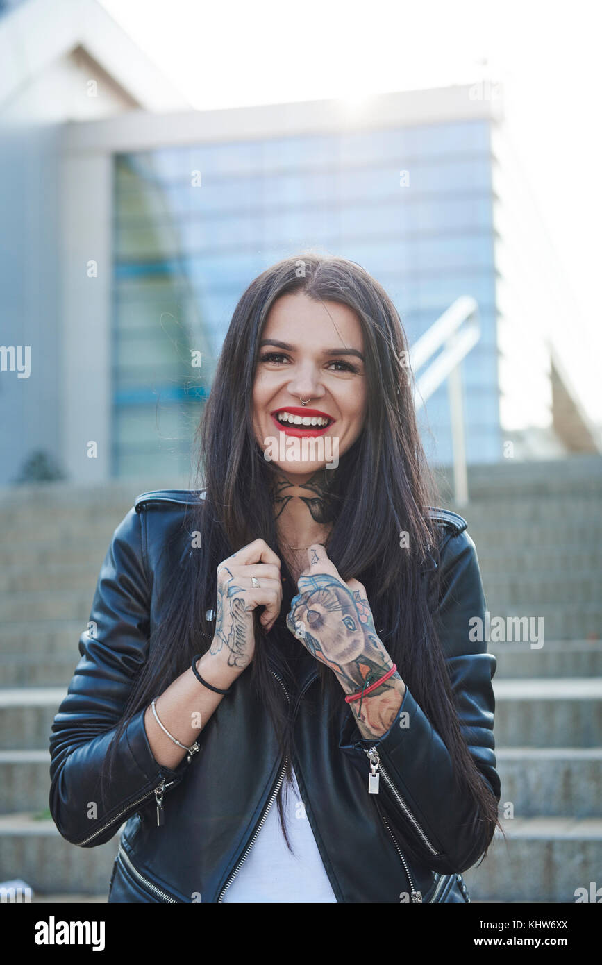 Portrait of young woman holding collars de veste, smiling, des tatouages sur les mains Banque D'Images