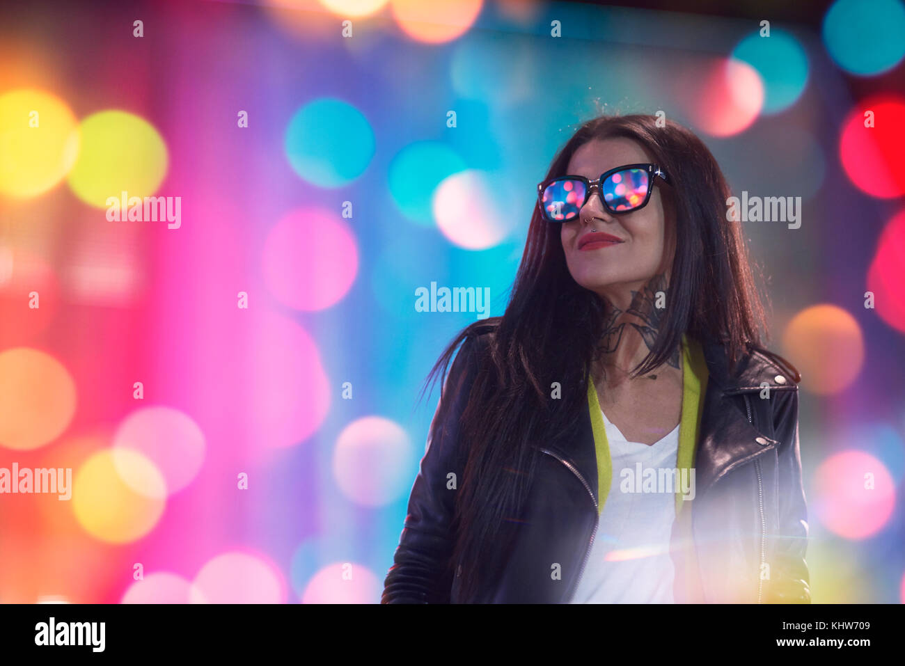 Portrait de jeune femme, à l'extérieur la nuit, les lumières reflétées dans les verres Banque D'Images