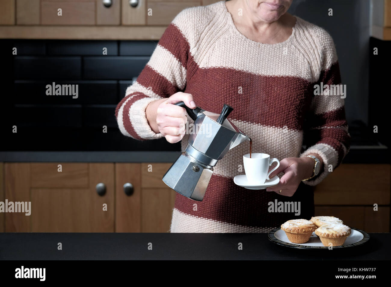 Une smart mais habillé décontracté woman pouring un café espresso à partir d'une machine à expresso cuisson molaire alors que debout dans sa cuisine à la maison Banque D'Images