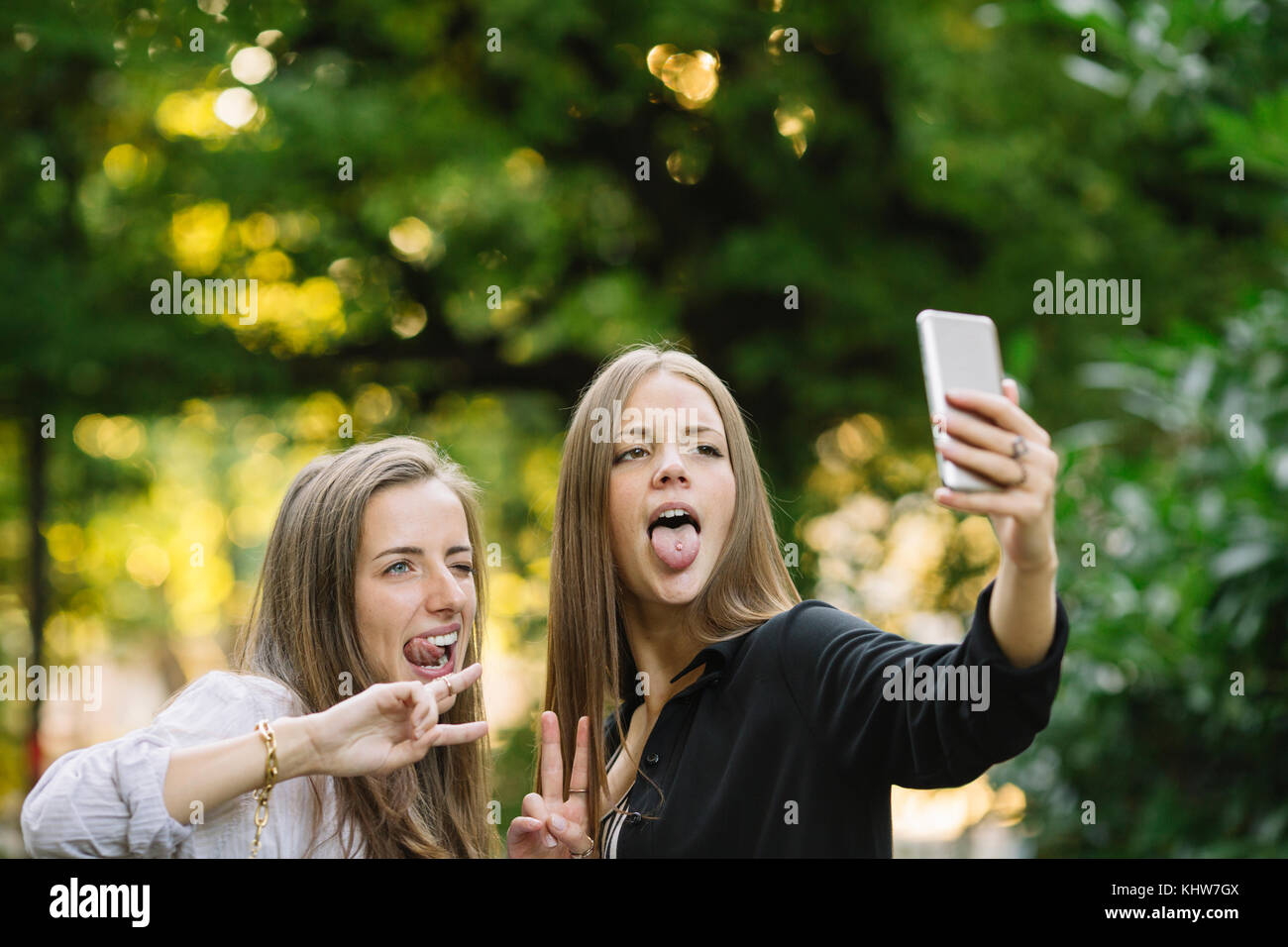Deux jeunes amies pulling faces pour smartphone en selfies park Banque D'Images