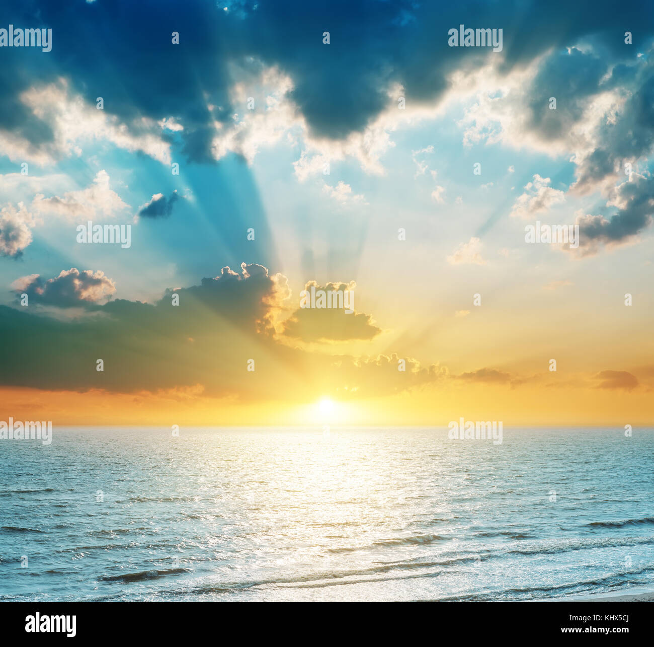 Coucher du soleil brillant dans les nuages au-dessus de la mer bleu Banque D'Images