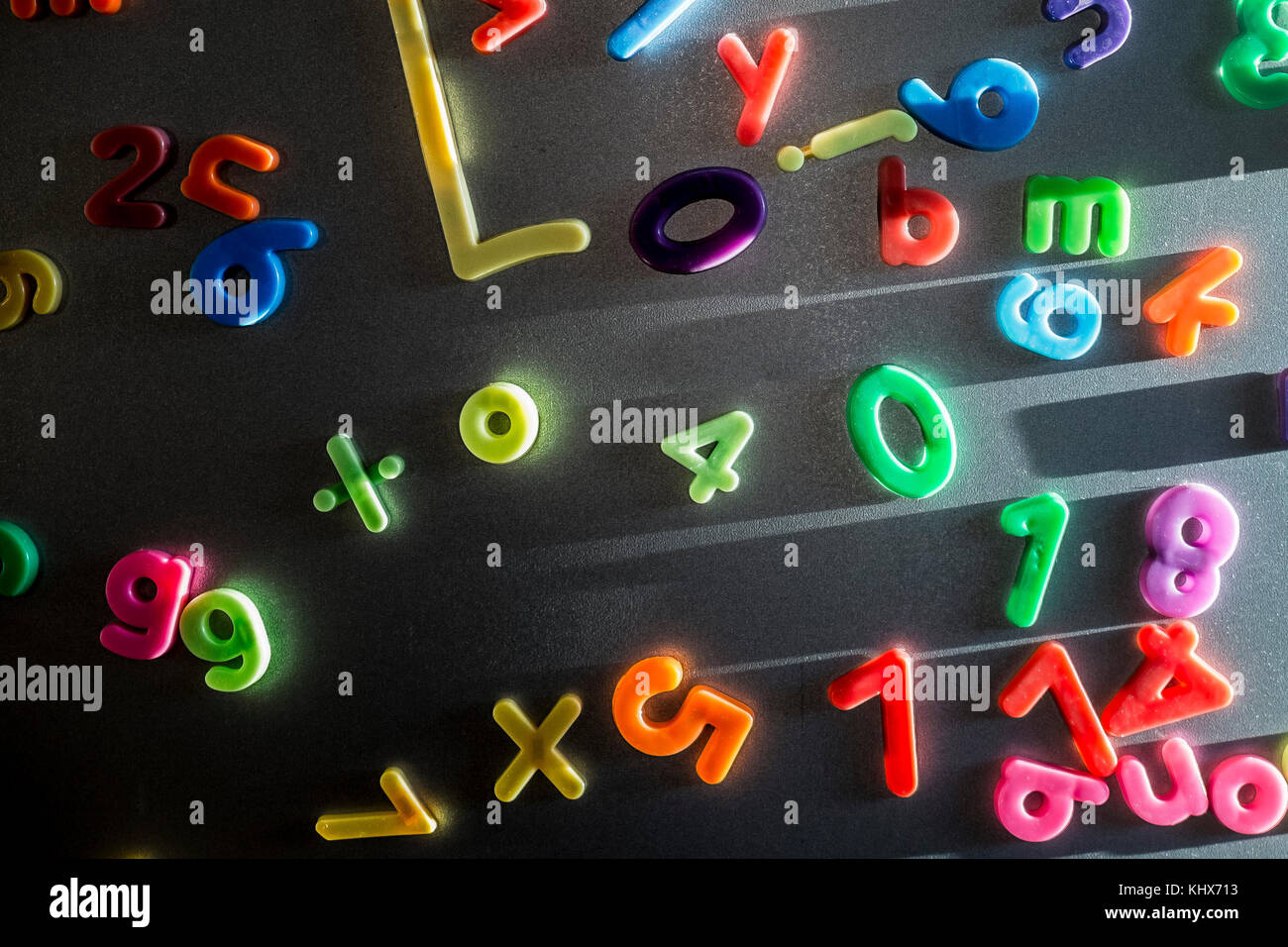Lettres et chiffres magnétiques en plastique colorés collés sur la porte d'un réfrigérateur. Banque D'Images