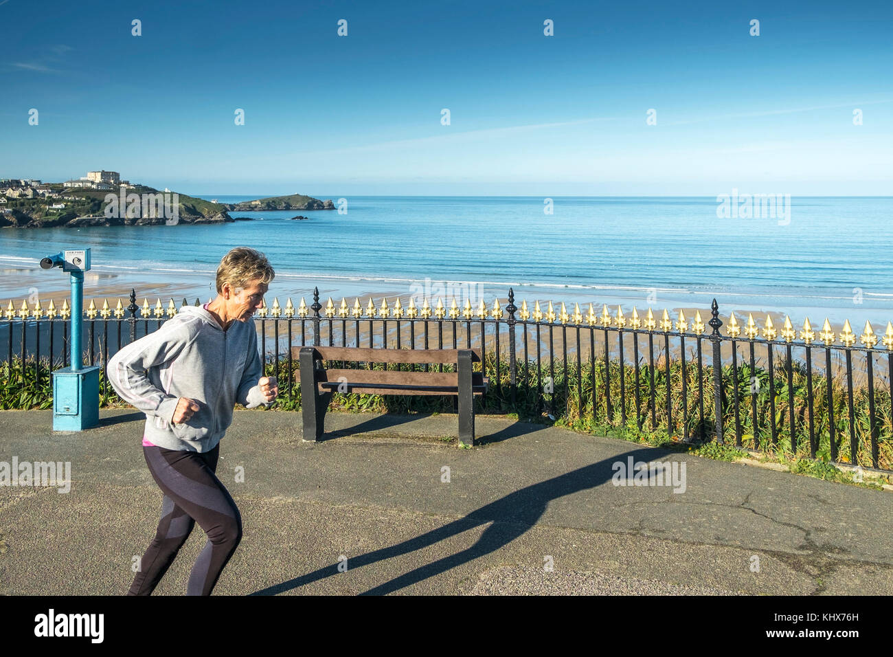 Une femme mûre jogging jogging jogging long du sommet de la falaise à Newquay Cornwall Royaume-Uni. Banque D'Images