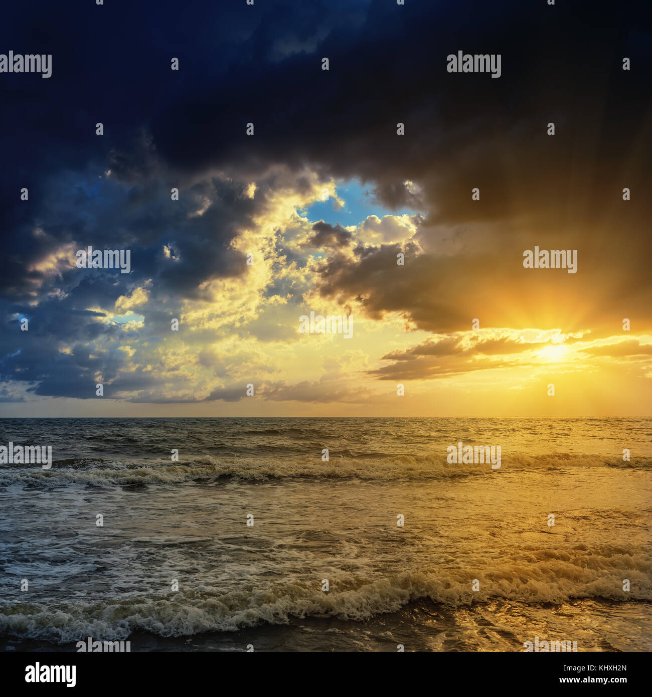 Coucher du soleil jaune dans des nuages sur la mer sombre Banque D'Images