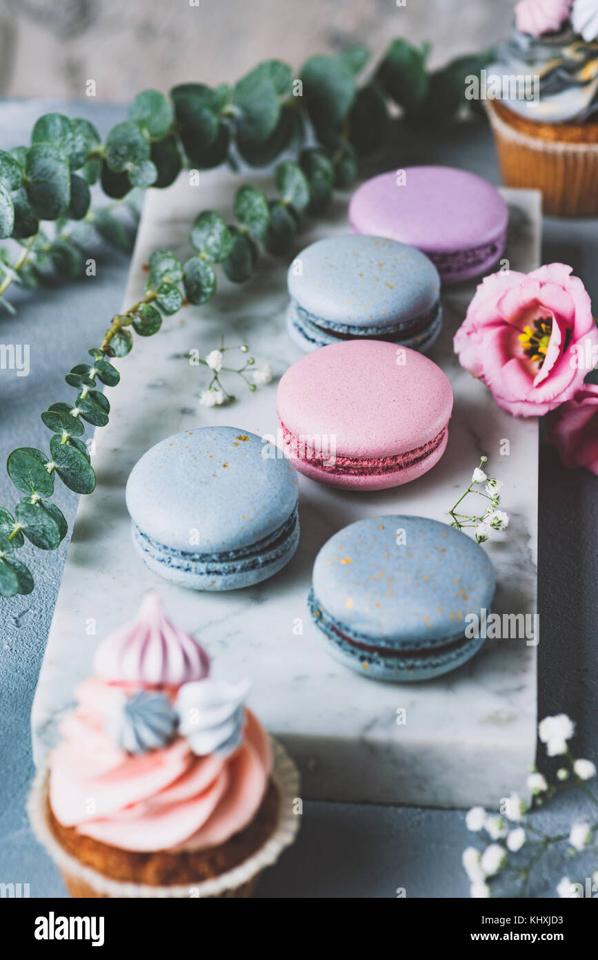 Macarons, cupcakes pastel et de fleurs sur fond de marbre. Bonbons de mariage, mariage cupcakes et macarons. Selective focus Banque D'Images