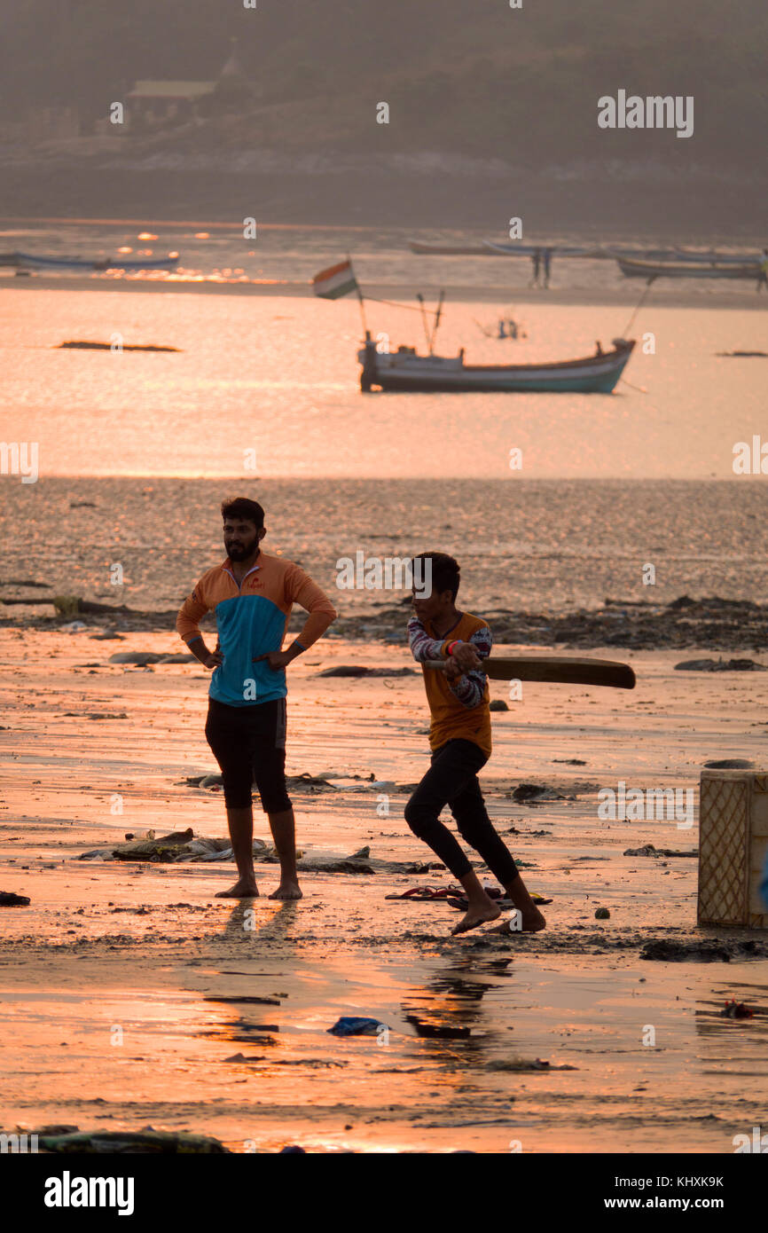 Les jeunes hommes à jouer au cricket au coucher du soleil sur la plage de versova, Mumbai Banque D'Images