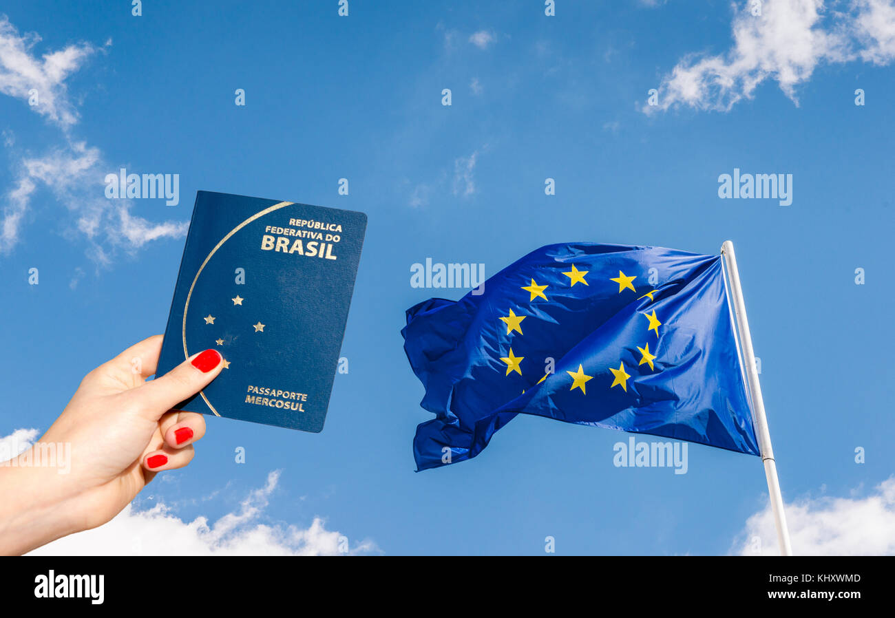 L'Union européenne (UE) drapeau contre un ciel bleu avec digital composite of woman holding un passeport brésilien Banque D'Images
