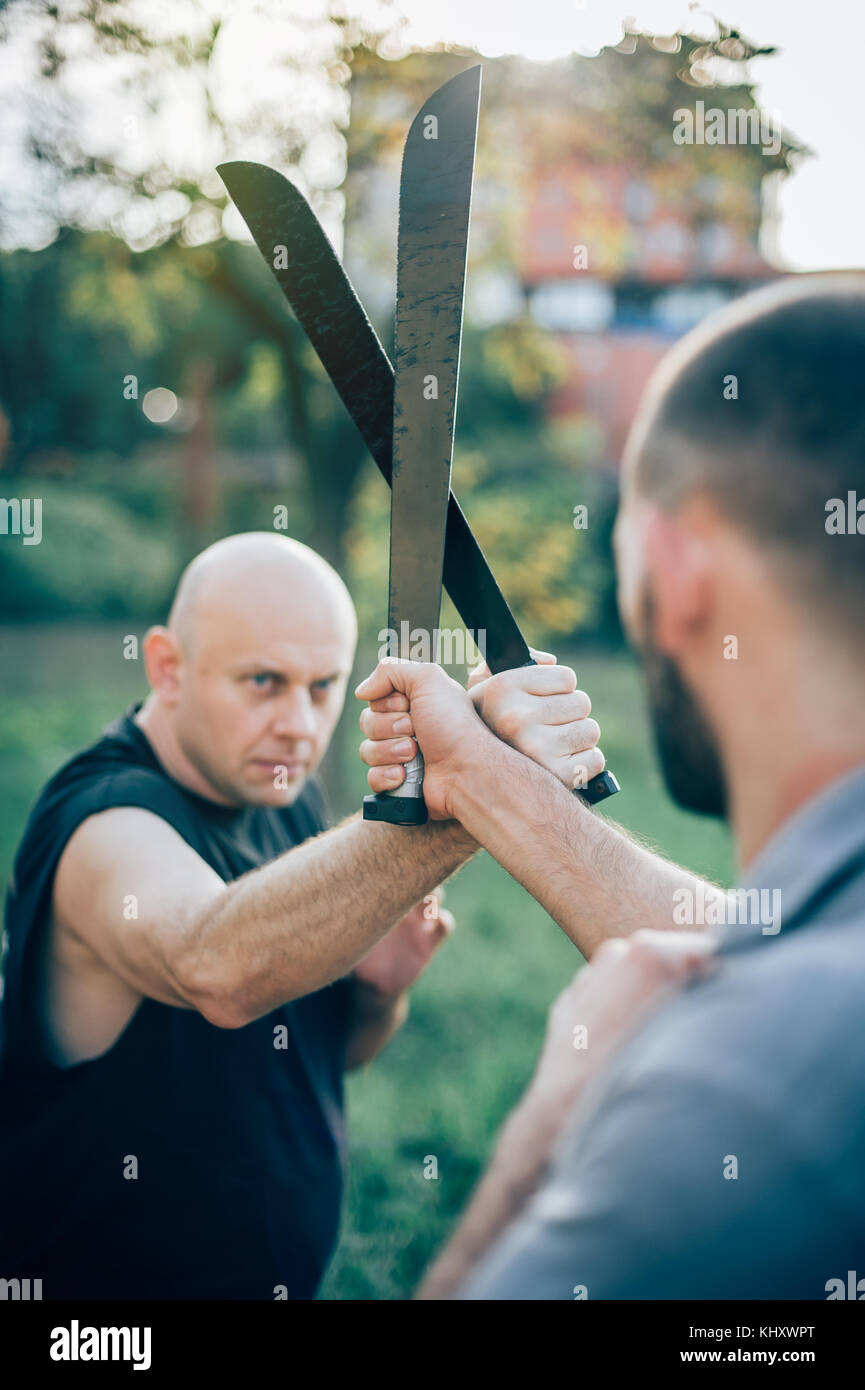 Un instructeur d'arts martiaux démontre le concept de combat de machettes.Formation d'armes à long couteau.Démonstration avec une vraie machette métallique Banque D'Images
