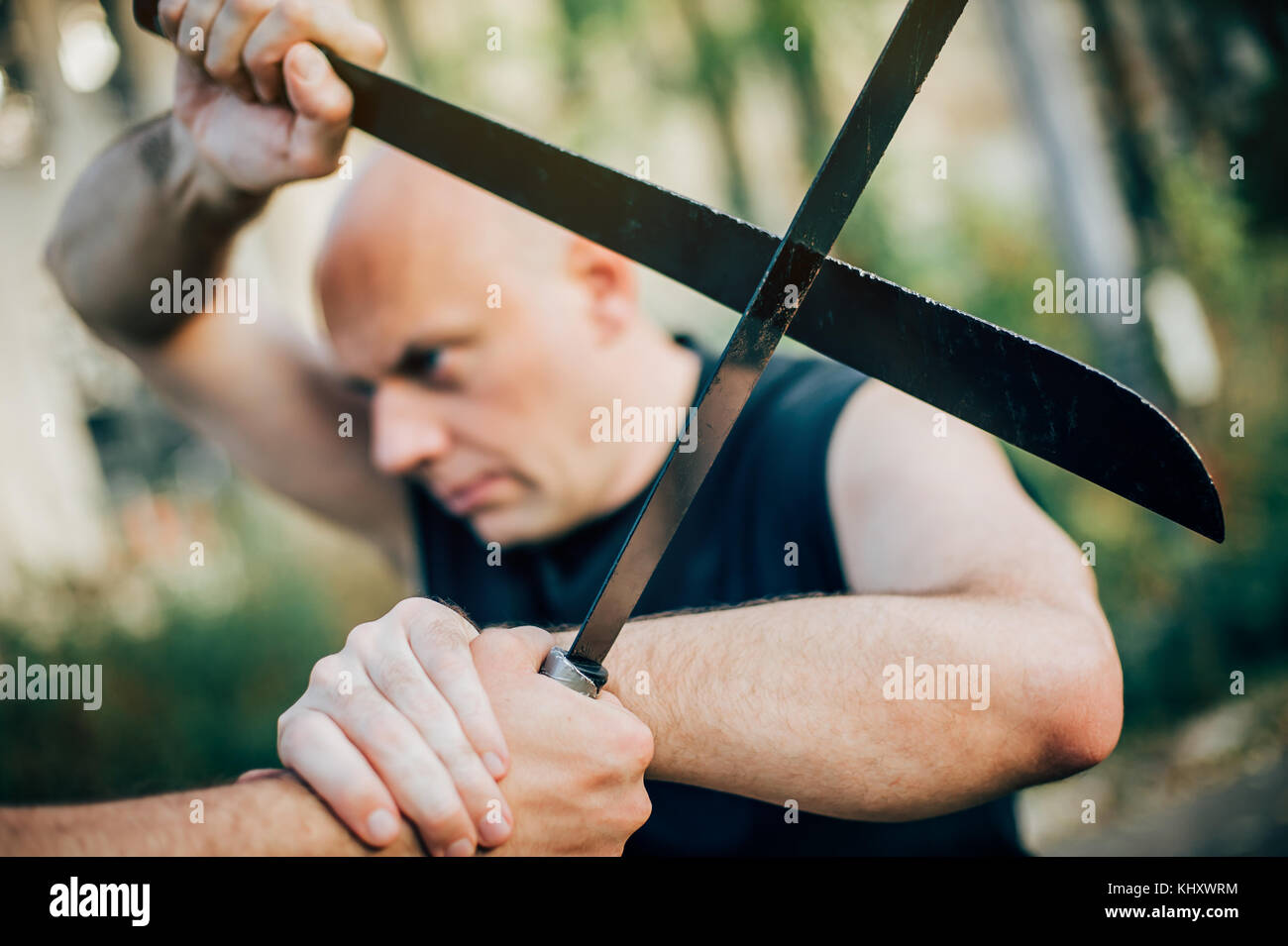 Un instructeur d'arts martiaux démontre le concept de combat de machettes.Formation d'armes à long couteau.Démonstration avec une vraie machette métallique Banque D'Images