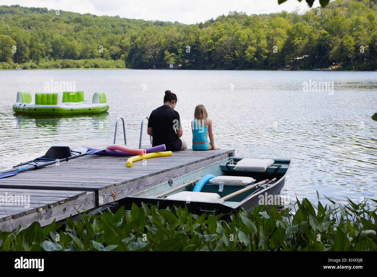 Deux filles assis sur jetée à côté lac, vue arrière Banque D'Images