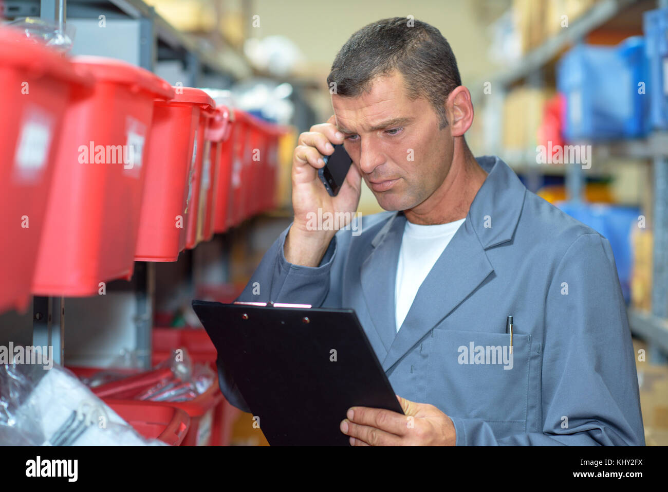 L'homme dans l'entrepôt sur téléphone à la concernée Banque D'Images