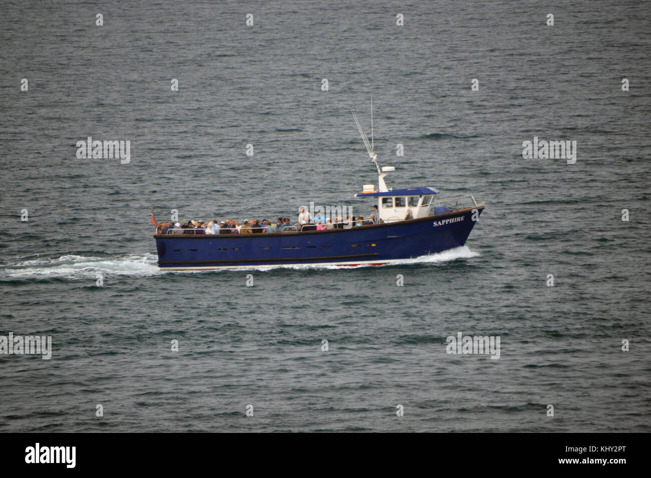 Le bateau de plaisance bleu (Saphir) laissant Hugh Town Harbour sur l'île de St Marys dans les îles Scilly, Royaume-Uni. Banque D'Images