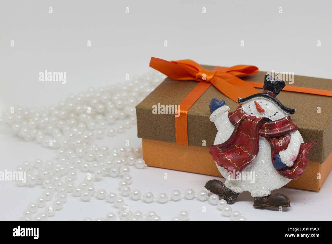 Boîte-cadeau avec un arc d'orange, perles blanches, toy snowman Photo Stock  - Alamy