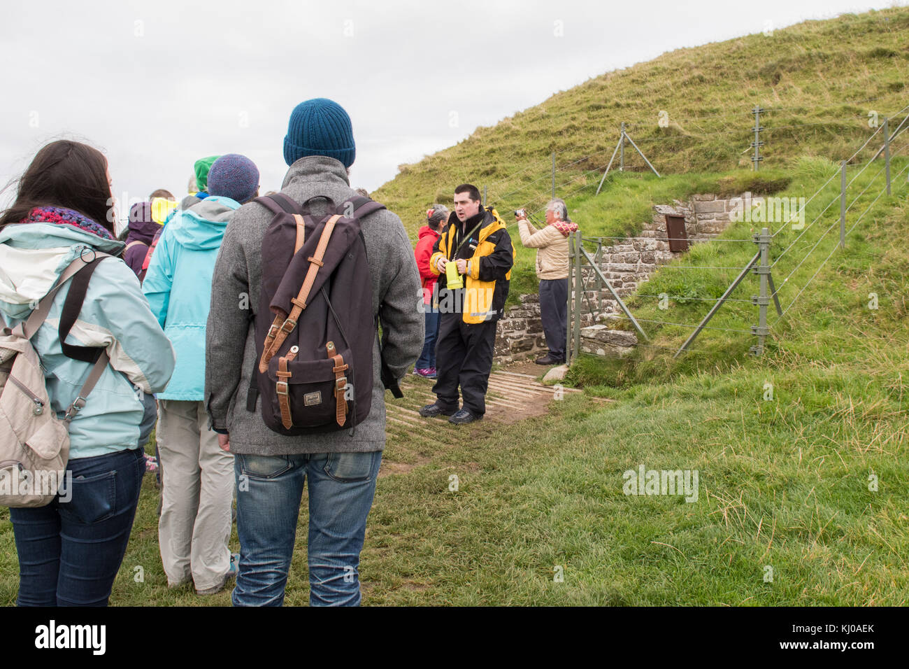 Guide parlant au groupe touristique à l'entrée du cairn à chambered néolithique de Maeshowe, partie du coeur du site néolithique d'Orcades, classé au patrimoine mondial Banque D'Images