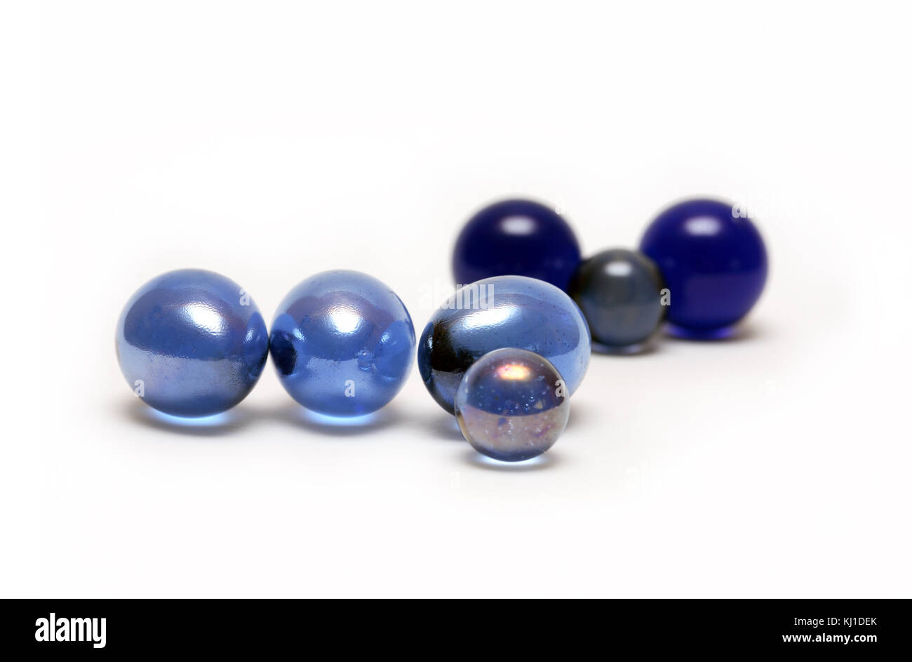 Divers quelques boules de verre bleu sur fond blanc Banque D'Images