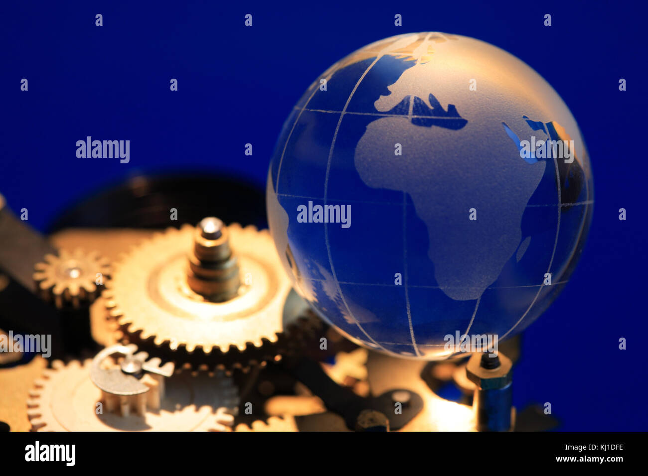 Globe en verre situé sur laiton mécanisme d'horloge avec des engrenages sur fond bleu foncé Banque D'Images