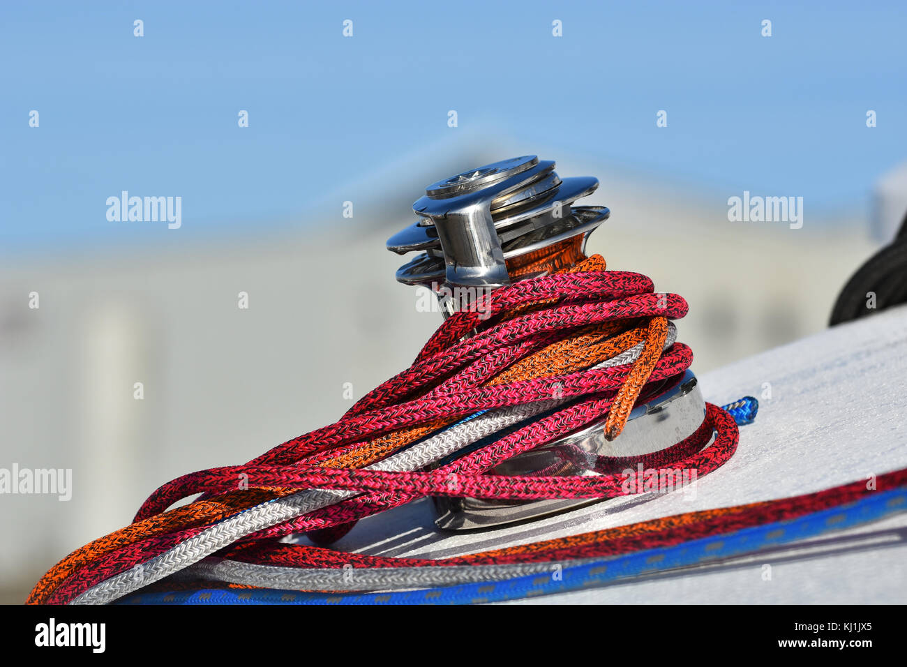 Détails d'une corde rouge sécurisée sur le treuil de bateau à voile, bateau racer concept. vue verticale. Banque D'Images