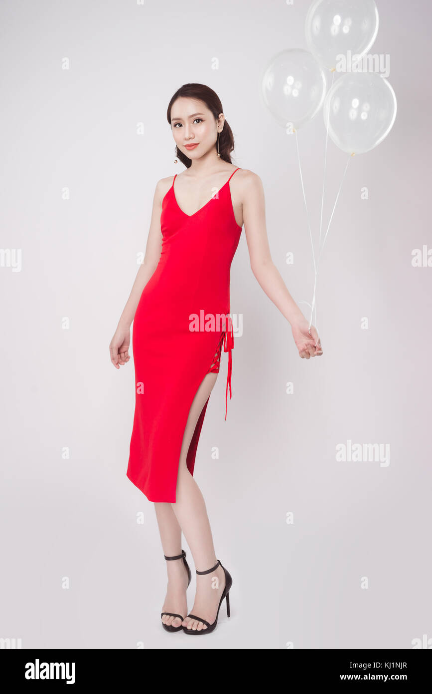 Belle femme asiatique en robe rouge avec des ballons pastel et looking up Banque D'Images