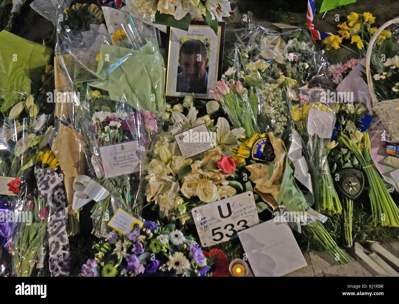 Fleurs et hommages décorer un portrait de l'agent de police assassiné, PC Keith Palmer, au Parlement, en face de vert le Parlement britannique à Londres, après le 21 mars 2017, une attaque terroriste, sur le pont de Westminster et le Parlement. L'attaquant de conduite d'un véhicule dans des piétons sur le pont de Westminster et une foule de personnes près de Banque D'Images