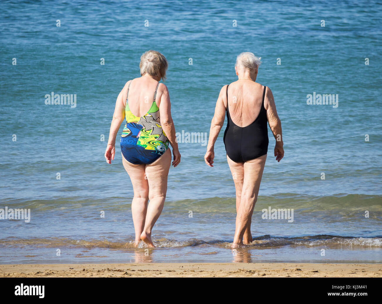 Vue arrière des femmes âgées qui vont nager après avoir suivi la classe de maintien quotidienne sur la plage en Espagne Banque D'Images