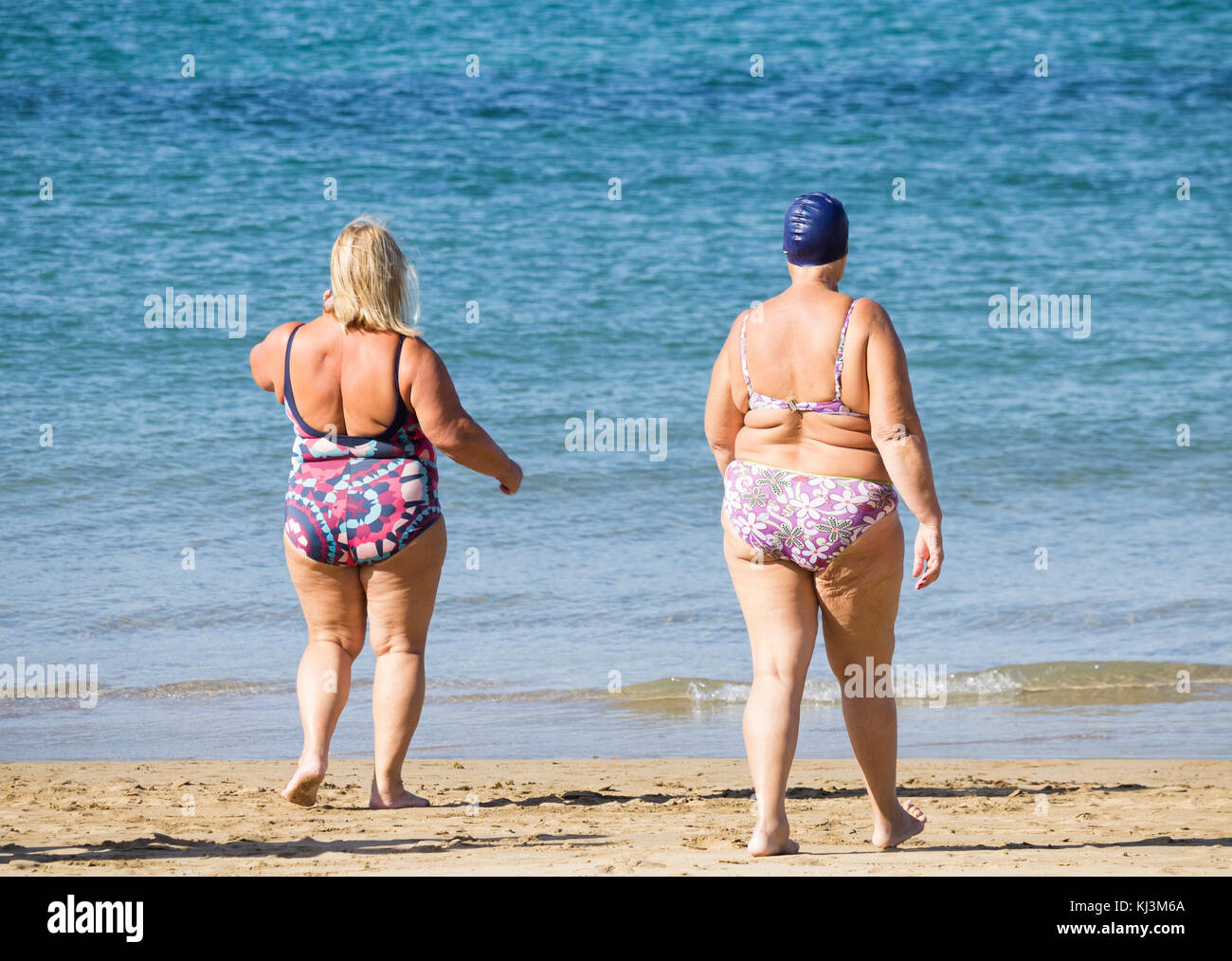 Vue arrière des femmes âgées qui vont nager après avoir suivi la classe de maintien quotidienne sur la plage en Espagne Banque D'Images