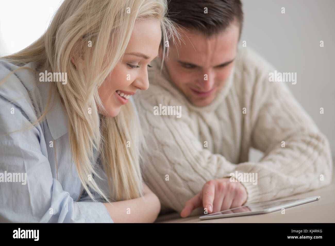 Jeune couple sur le sol en face de cheminée internet surf using digital tablet on froide journée d'hiver Banque D'Images