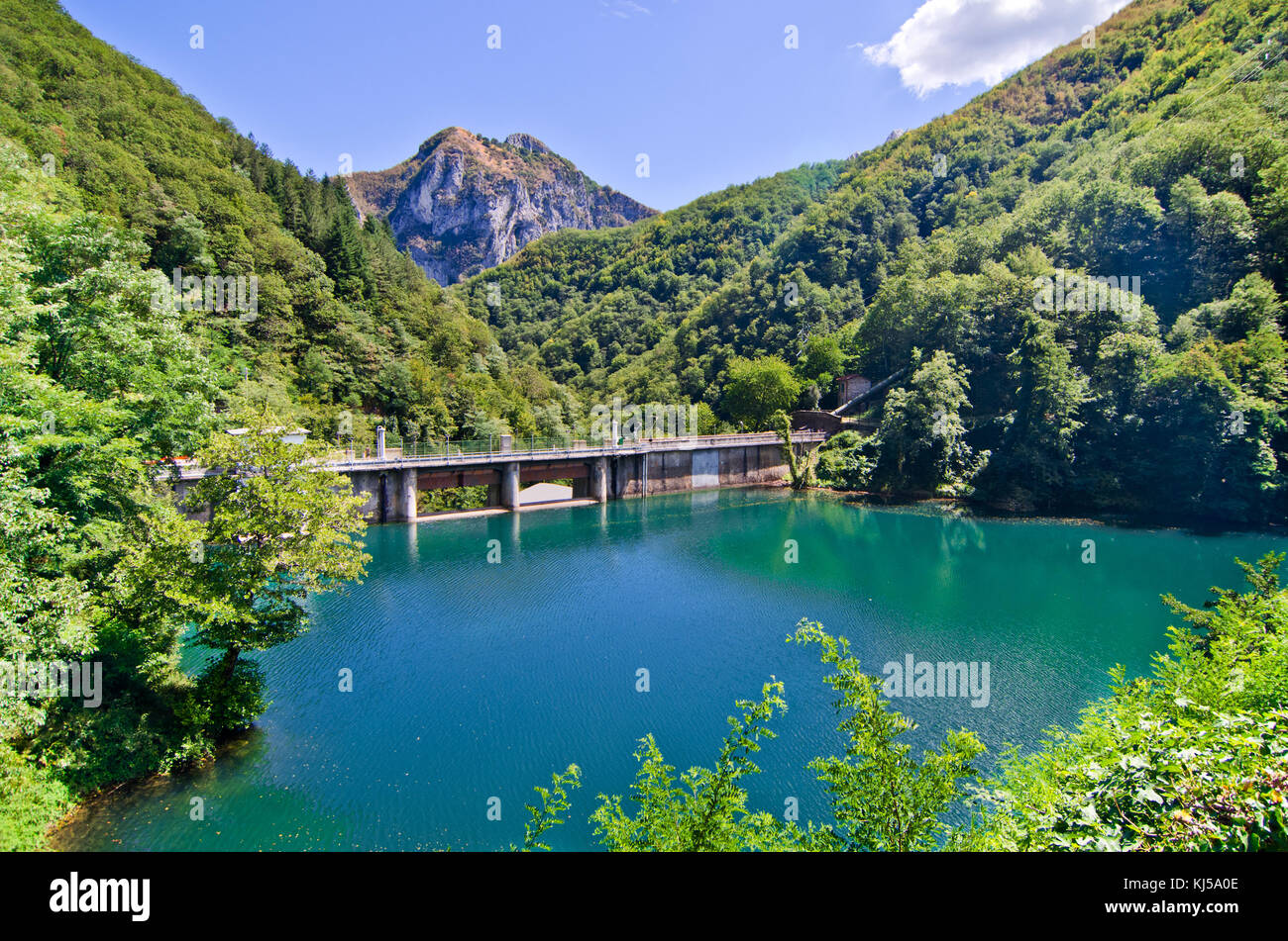 Barrage avec le bleu et vert d'eau forme un petit lac au milieu des montagnes couvertes de forêts denses Banque D'Images