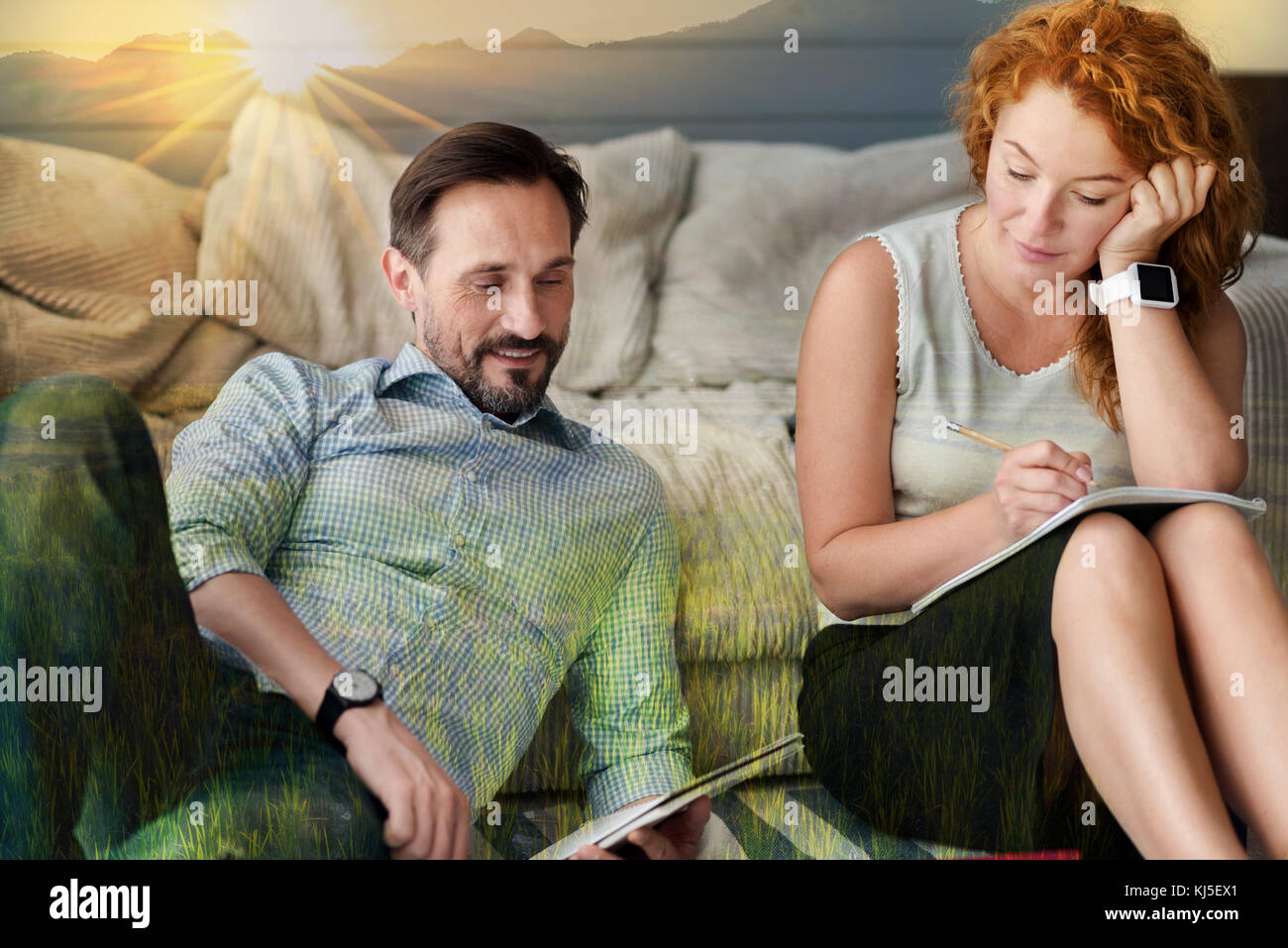 Femme calme prendre des notes pendant que son petit ami assis près de et de la lecture Banque D'Images