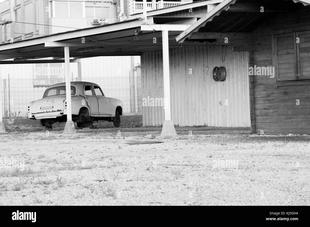 Vieille voiture sans un de ses roues et suspendu de l'image murale en noir et blanc Banque D'Images