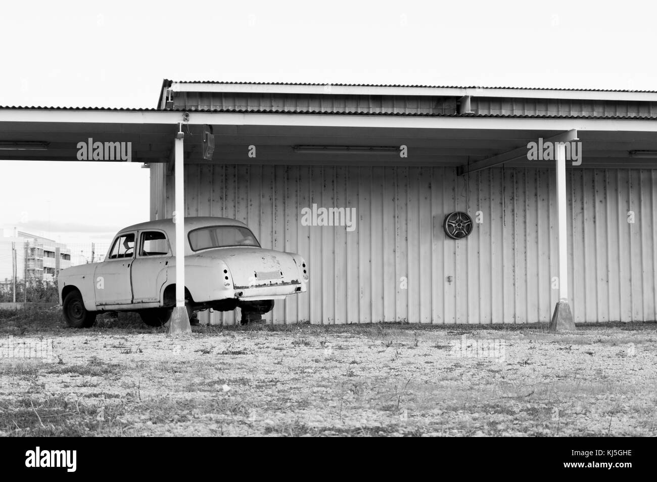 Vieille voiture sans un de ses roues et suspendu de l'image murale en noir et blanc Banque D'Images