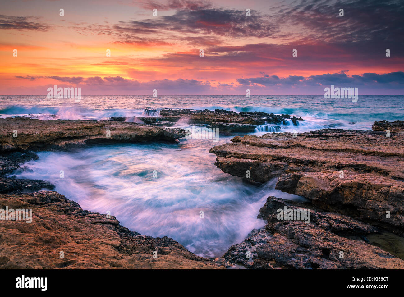 Vagues se brisant sur les rochers à el banyets dans El Campello Espagne à l'aube. l'eau est forcée vers le bas un canal vers le point de vue Banque D'Images