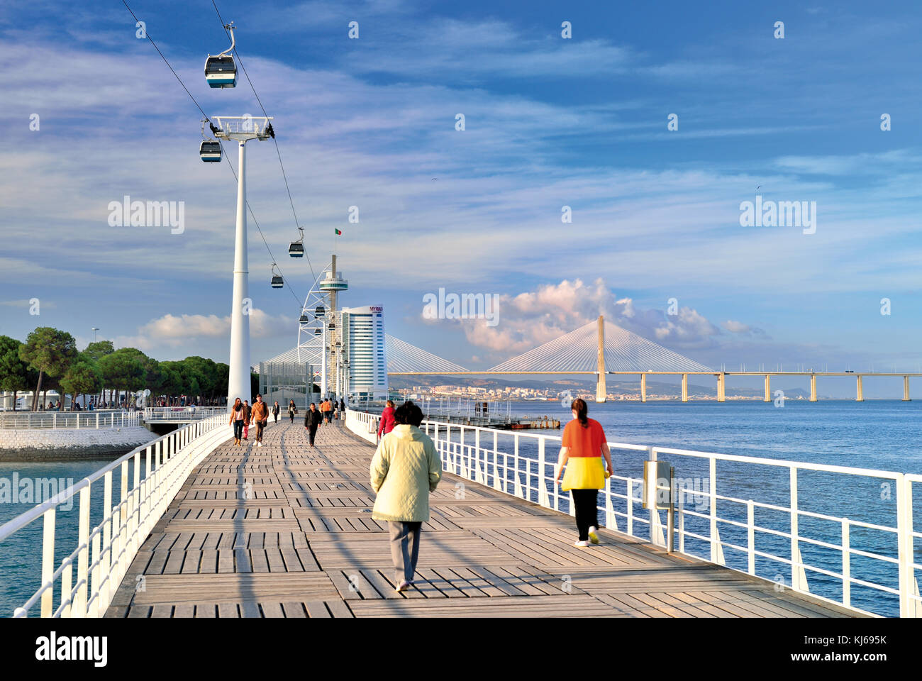Personnes passant le pont piétonnier entouré par l'architecture moderne, télésiège et pont Vasco da Gama Banque D'Images