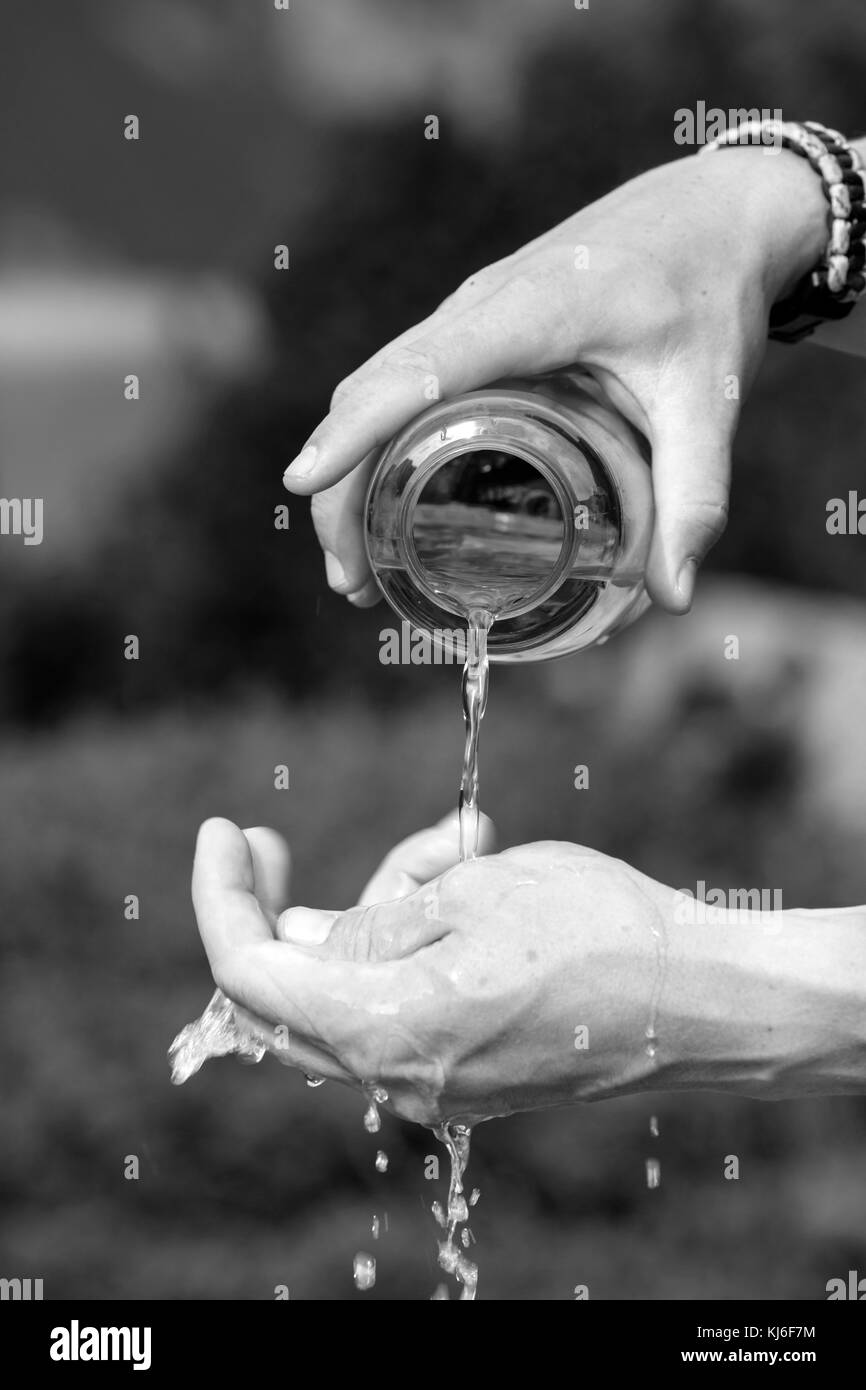 Randonneur verse de l'eau d'une bouteille d'eau sur ses mains Banque D'Images