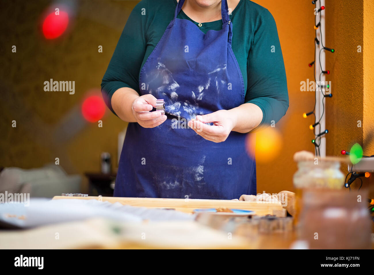 La photo en gros plan de femme debout derrière une table de cuisine à la maison, la tenue d'un emporte-pièce dans ses mains. Les pâtisseries de Noël concept. Banque D'Images