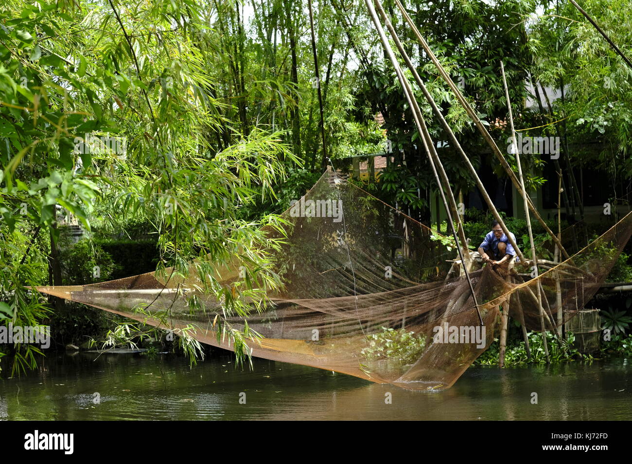 Asian man réparant un filet de pêche de levage à côté d'une rivière au vietnam Banque D'Images