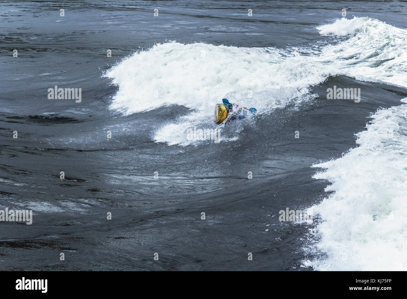 Un kayakiste commence un rouleau intentionnelle dans des vagues énormes à Sechelt Rapids (kookumchuck «'), l'une des plus rapides du monde passe à marée (Colombie-Britannique). Banque D'Images