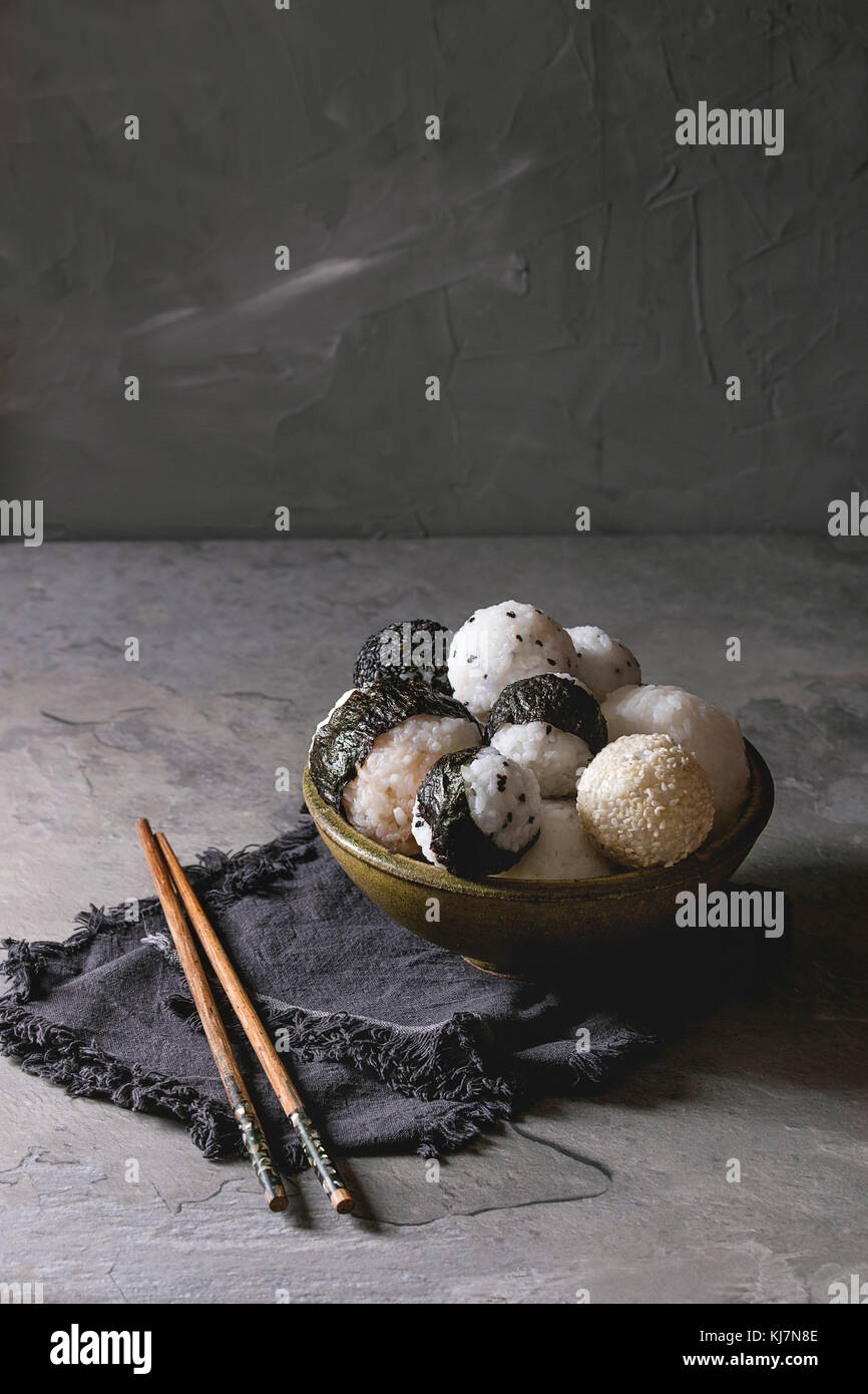 Bol avec différentes tailles de boules de riz et sésame noir avec des Algues Nori, servi avec des œufs durs, de la sauce de soja, des baguettes sur le tableau gris. Asian sty Banque D'Images