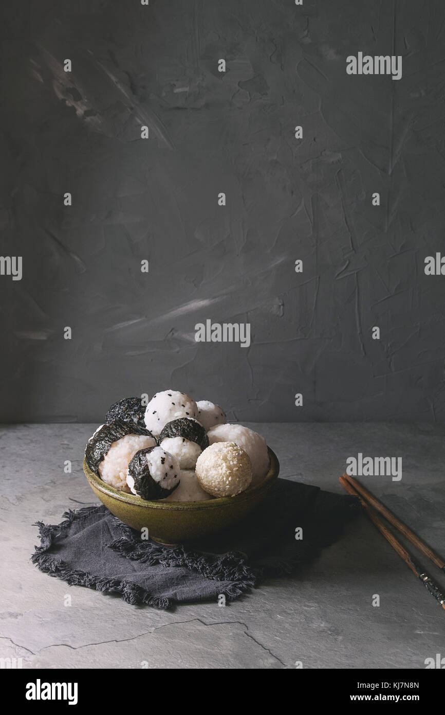 Bol avec différentes tailles de boules de riz et sésame noir avec des Algues Nori, servi avec des œufs durs, de la sauce de soja, des baguettes sur le tableau gris. Asian sty Banque D'Images